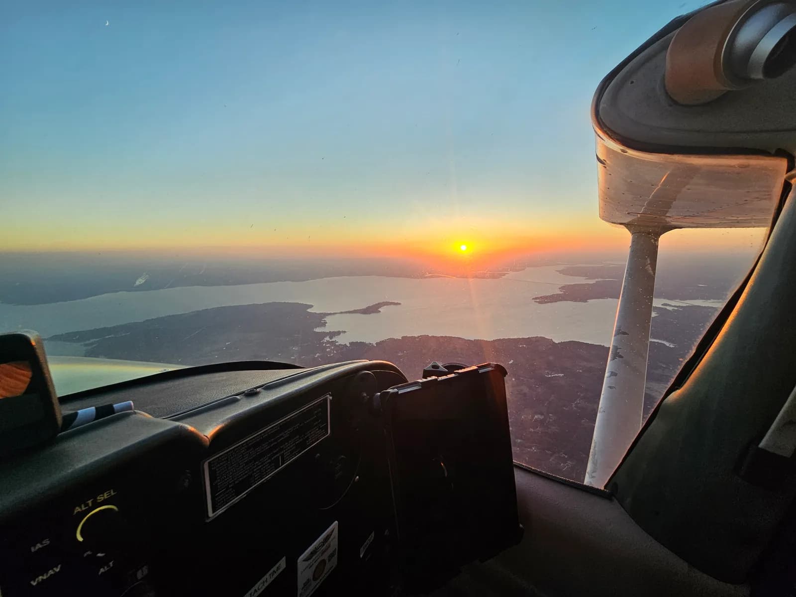 View from the Cessna 172H cockpit of a sunset over a Texas lake